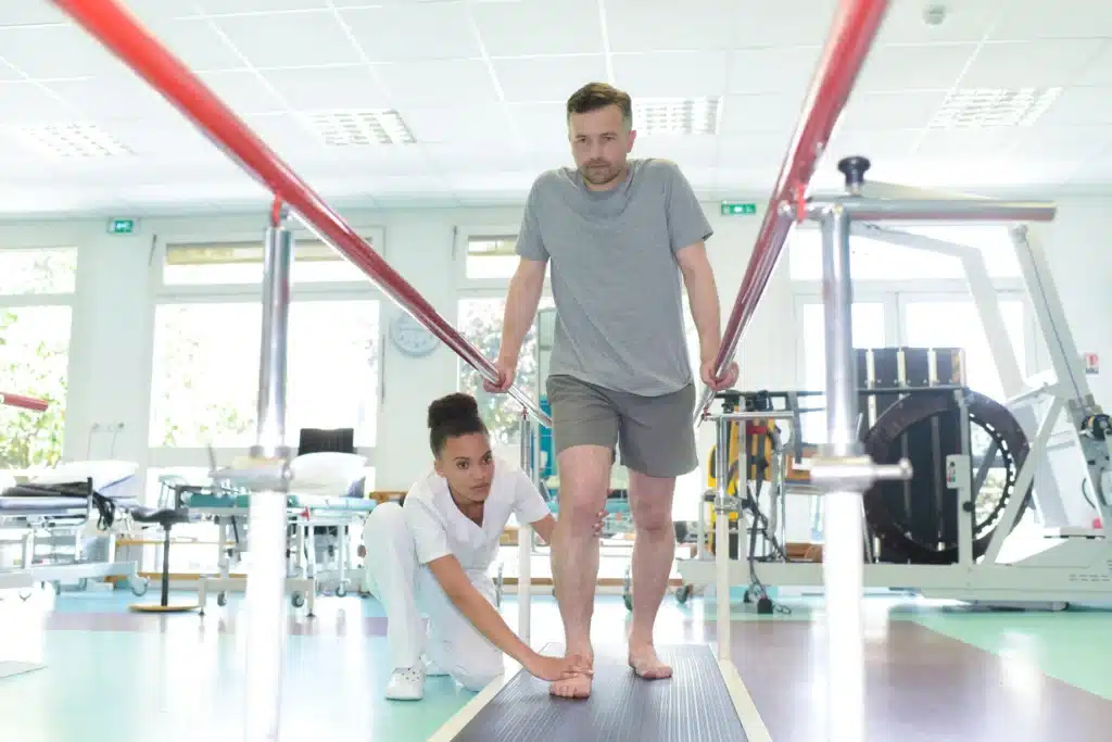a therapist helps a patient gait training in habilitative vs rehabilitative therapy